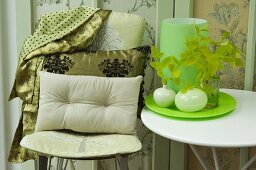 Cushions on chair and side table holding vases on tray