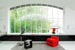 Roter Sessel und schwarzer Beistelltisch in minimalistischem Wohnraum mit Fensterfront