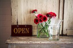 Vase of flowers and OPEN sign on cabinet