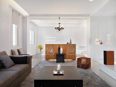 Zeitgenössischer Wohnraum im mit Sofa und Couchtisch aus dunklem Holz und transparenten Stühlen vor halbhohem Raumteiler