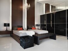 Designer Schlafraum - Einzelbetten auf dunklem Holzgestell und Holzpanelen an Wand neben Schrankwand mit schwarzen Glasschiebetüren
