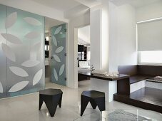 Schwarze Hocker in weißem, offenen Wohnraum mit Glastrennwand und abstraktem Muster