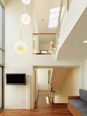 Double-height foyer with gallery and group of pendant lights hanging from ceiling