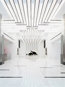 Weisser minimalistischer Raum mit Lichtbändern an Decke und Blick auf Klavierflügel