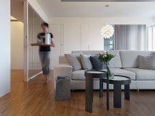 Graues Beistelltischset vor heller Polstercouch in minimalistischem Wohnraum