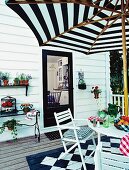 White terrace with table, chairs, parasol, plants and black and white chequered floor