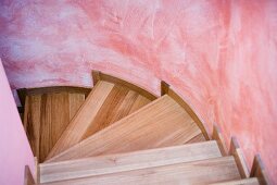 Treppenstufen aus Holz an pinkfarbener Treppenhauswand