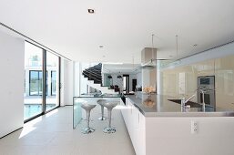 Offener Wohnraum in Weiß mit Designer Küchenblock und Barhockern