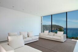 Helle Sofagarnitur im minimalistischen Wohnraum mit Fensterfront und Meerblick