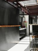Bar stools at kitchen counter and black sliding wall in front of designer kitchen