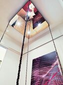 Mirror element with cables and spotlights as ceiling light and modern artwork on wall
