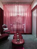 Vorraum mit Beistelltischset auf grauem Teppich und neobarockem Stuhl vor rotem transparentem Vorhang