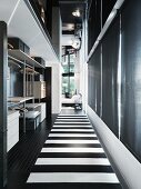 Open wardrobe and black and white striped flooring in the hallway of a loft-like living room