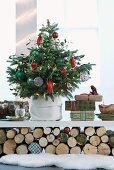 Decorated Christmas tree and presents on white shelf resting on stacked logs