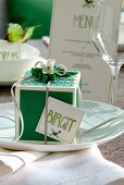 Gift box with ribbon and name tag on place setting with wine glass