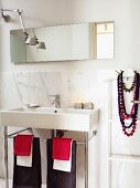 Modern washstand with towels hanging on metal base frame against marble wall panel