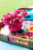 Pink flowers in bowl with pink knitted cover on floral tray