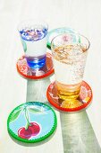Drinking glasses of sparkling water on colourful coasters