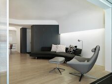 Designer sofa and armchair in a modern living room with suspended ceiling and indirect lighting