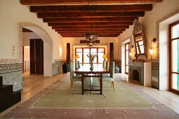 Moderne Esszimmergarnitur au einem großen Teppich im rustikalen Raum mit Holzbalkendecke und orientalischem Flair
