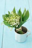 A bunch of lilly of the valley in a tin cup