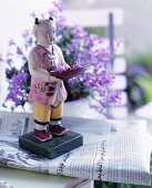 Painted, Asian wooden figure standing on a newspaper