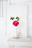 Rhododendron (variety: 'Abendsonne') in white vase on table in front of wooden panel