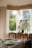 Set table and collection of lanterns in dining room bay window