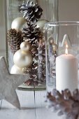 Arrangement of white pillar candle in lantern and Christmas decorations in glass jar