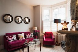 Raspberry coloured velvet furniture in living room with Graham and Green porthole wall mirrors