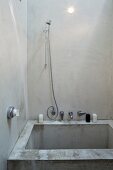 Minimalist shower stall made from raw concrete with stainless steel fittings