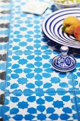 Blau-weiß geflieste Tischplatte mit floralem Muster und blau-weißem Geschirr