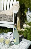 Tray set with refreshing drinks in long grass in front of white garden chair