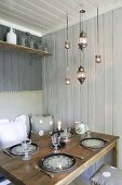 Raumecke mit gedecktem Esstisch in skandinavischem Holzhaus mit Sitzbank und Rückenpolster an der Wand; harmonische Farbgestaltung
