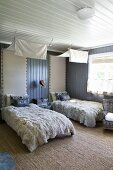 Twin bedroom with cosy fur blankets and scatter cushions on beds below white lengths of fabric used as canopies and upholstered headboards