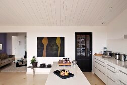 Modern kitchen with a white island under a wood ceiling in a simple living room