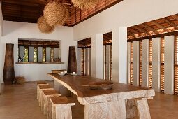 Dining table with stools and large urns in open plan beach house retreat in the Indian state of Goa