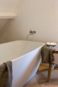 Moderne Badewanne mit Wandarmatur und Holzschemel