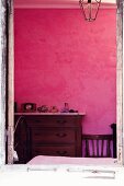 Antike Holzkommode mit Marmorplatte an pinkfarbener Schlafzimmerwand
