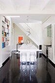 Küche mit weißem Küchenblock und Barhockern aus transparentem Kunststoff auf dunklem glänzendem Holzboden