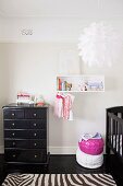 Nursery in black and white - modern pendant lamp above zebra-patterned rug and black vintage chest of drawers