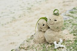 Man and woman figures made of sand on beach