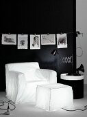 Armchair-shaped and pouffe-shaped lamps below black and white animal photos on black wall