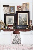 Sammlung von Heiligenbildern und -figuren am Kopfende eines Bettes; mit Madonnenbild und Herzen bedrucktes Dekokissen