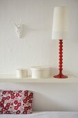 A decorative retro lamp and round boxes on a white shelf