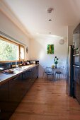 Strip window running parallel to kitchen counter in modern kitchen with pale wooden floor