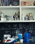 Items stored on open shelving unit in contemporary kitchen with chalkboard