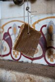 Natural soap on a rope hanging in front of tiles with original pattern in kitchen of house in southern France