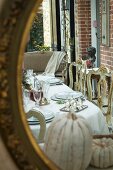 Reflection of dining table with elegant place settings and gilt, Baroque chairs
