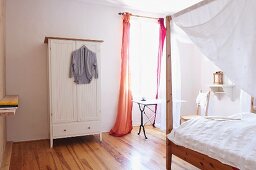 Helles Schlafzimmer mit weißem Wäscheschrank und Himmelbett
